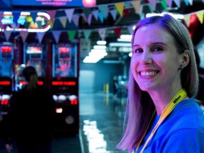 Volunteer smiling at camera while her face is lit with purple lighting.