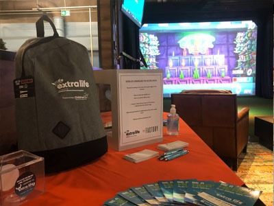 Grey backpack on table with the words an Extra Life logo on it.