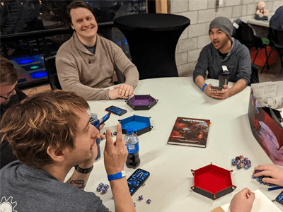 Group of five people sitting around a table playing Dungeons and Dragons.