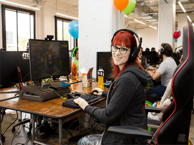 Gamer sitting at desk in a gaming chair, smiling at the camera.