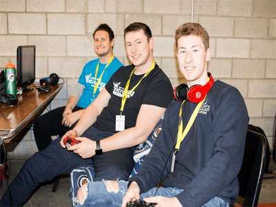 Group of three men smiling, holding controllers.