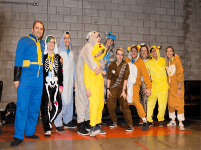 Group of people standing together wearing themed onesies.