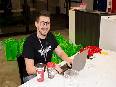 Extra Life volunteer working at a laptop while smiling.