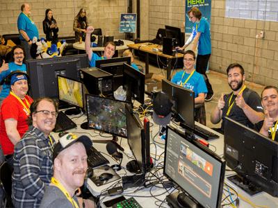 Two rows of gamers sitting at desks, playing video games on computers.